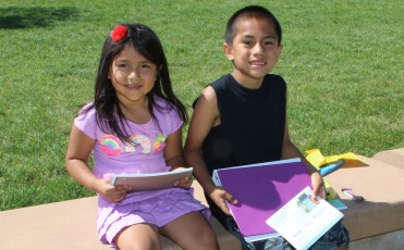 A girl and a boy holding school supplies that they received at the Back 2 School Bash.